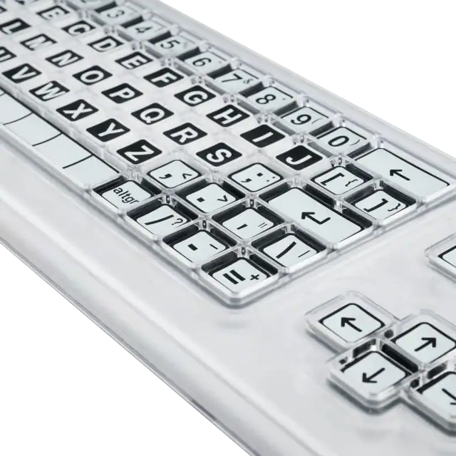 Close up image of a black and white keyboard with a clear perspex keyguard separating the keys.