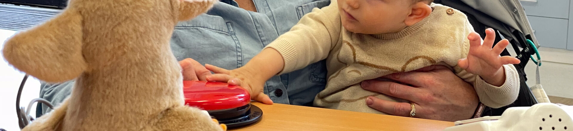 A young child reaching out to touch a Big Red switch to activate a toy.