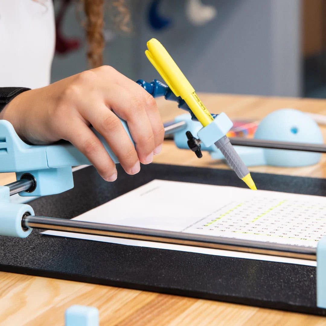 A person's hand placed in the Guided Hands Assistive Technology device with a pencil placed in the handpiece.