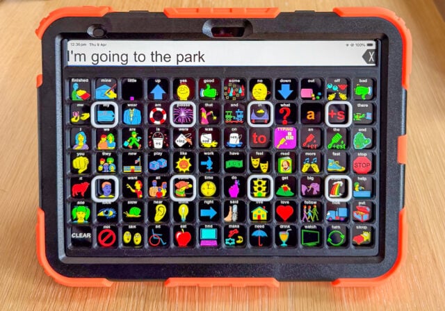 iPad in a rugged case displaying an AAC communication app LAMP Words for Life with high contrast symbols and a custom tactile AAC keyguard. The phrase in the message window reads “I’m going to the park.”