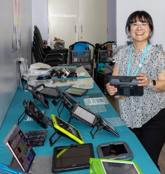 Speech pathologist displaying AAC communication devices and assistive technology equipment used for communication assessment and support.